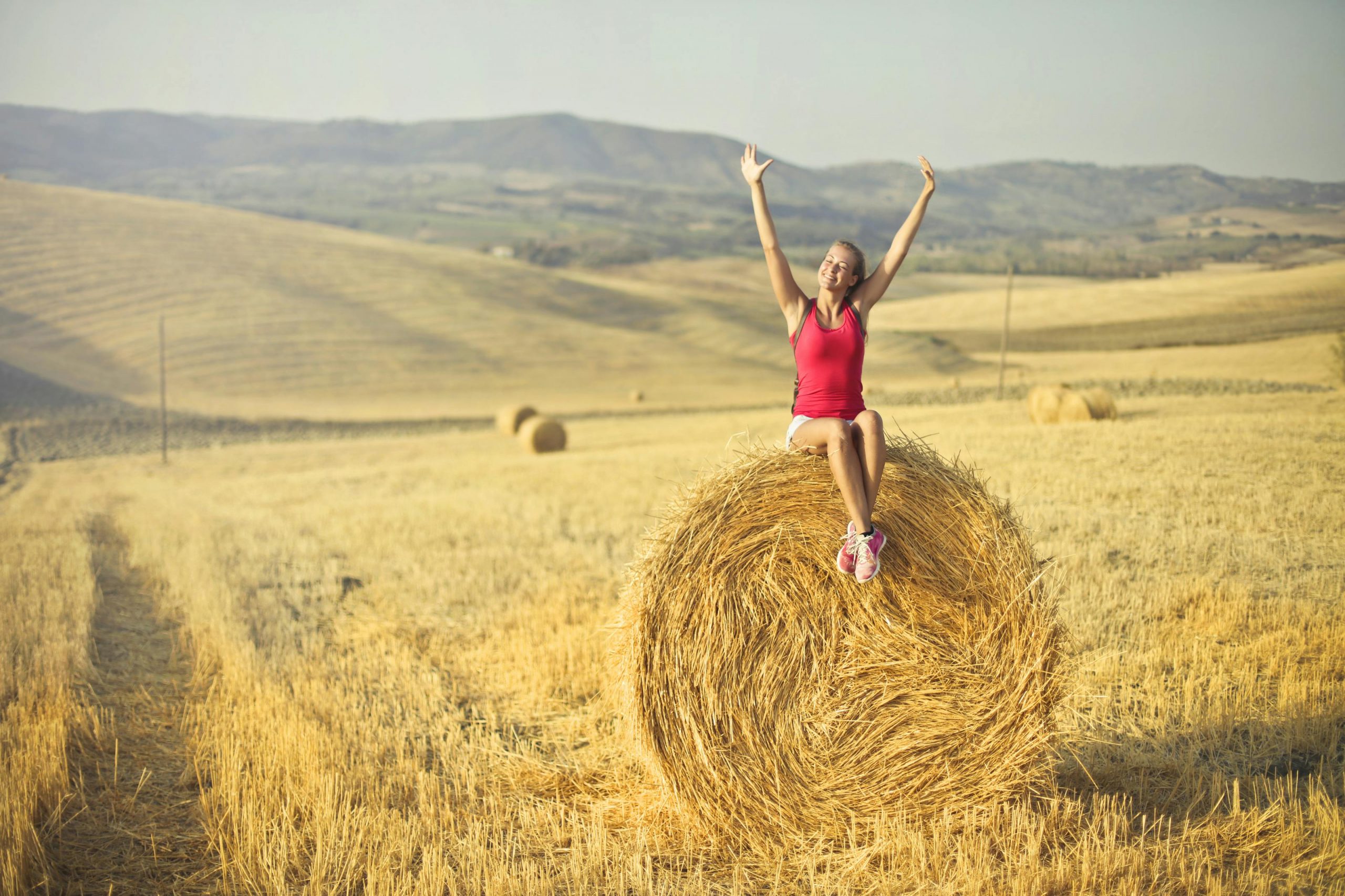 A propos 2 une fille qui lèvre les bars en signe de voctoire assise sur une botte de paille